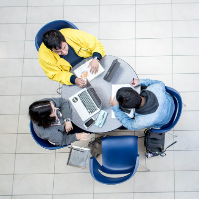 3 students studying at table with laptops from above